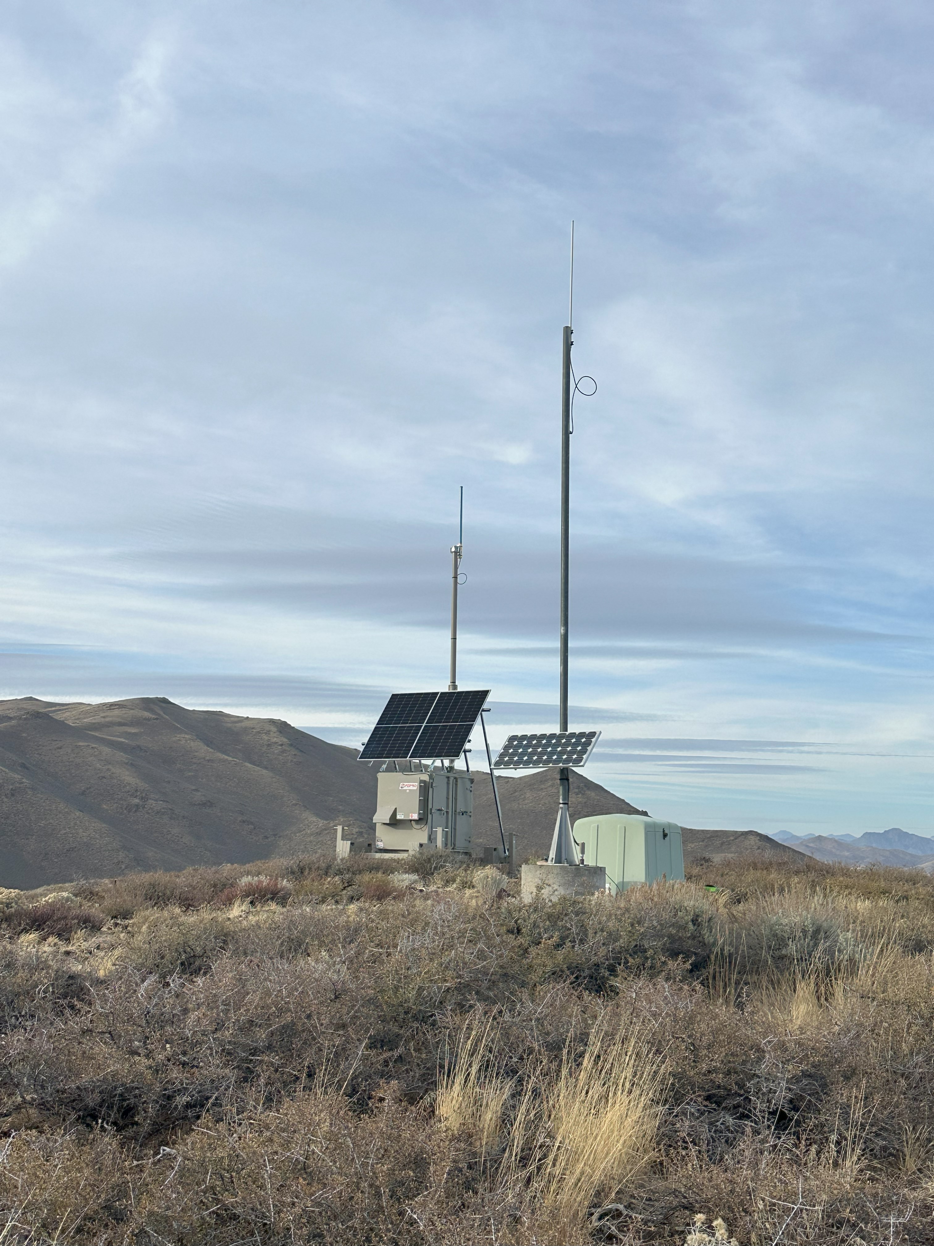 Completed remote communications site with solar array and antenna mast on a ridge
